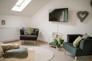 a living room with two chairs and a tv on the wall at Ferienwohnung Landliebe in Pfullendorf