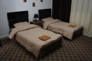 two beds in a hotel room with towels on them at Petra entrance Apartment in Petra