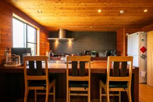 a kitchen with a counter with four chairs around it at みみずく山荘 Mimizuku Lodge in Myoko
