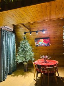 un comedor con una mesa roja y un árbol de Navidad en Mountain Shadow Cottage in Racha, en Ghebi
