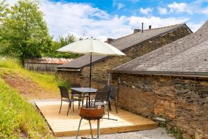 une table et des chaises avec un parasol sur une terrasse en bois dans l'établissement Les palis de Sert, à La Chapelle-de-Brain