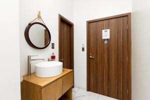 a bathroom with a sink and a wooden door at Hotel H4 Olanchito in Olanchito