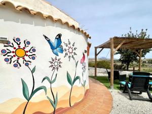 a wall with a mural of flowers and a butterfly at Cave Houses Ed, Yara and Nadieh with PRM facilities in Margen de Abajo