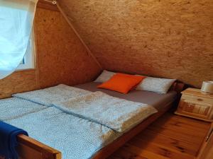 DobrogoszczCottage in Koscierzyna with Lake Nearby的一间小房间，里面有一张床，上面放着一个橙色的枕头