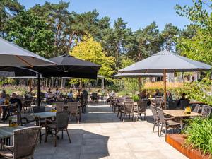 费尔德霍芬Chalet by Park Pond in the Netherlands的配有桌椅和遮阳伞的户外露台