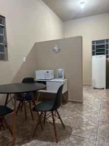 a kitchen with two tables and a white refrigerator at Casa aconchegante a poucos passos da Basílica in Aparecida