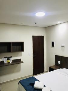 1 dormitorio con cama y puerta marrón en Hotel Pinheiros - 8 Min do Transamérica Expo Center e 18 Min Autódromo Interlagos, en São Paulo