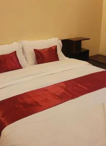 a large bed with red and white sheets and pillows at STERLEON HOTEL RIVERSIDE in Nairobi