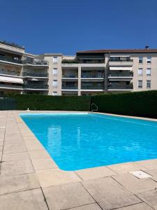 Perollier - CI - Lyon 2 - Bedroom apartment with balcony and pool في إيكولي: حمام سباحة أزرق أمام مبنى