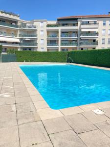 Perollier - CI - Lyon 2 - Bedroom apartment with balcony and pool في إيكولي: حمام سباحة أزرق أمام مبنى +4 صور