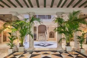 a lobby with two palm trees and a staircase at VG - Villa de Andas suites in Cádiz