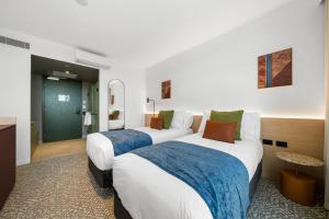 a hotel room with two beds with blue and white sheets at Urban Rest Hackney Hotel in North Adelaide