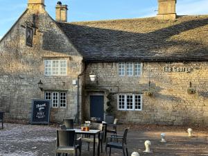 巴斯The Coach House at The Grange的一座石头建筑,前面设有桌椅 更多11张照片