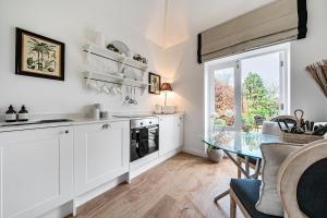 巴斯The Coach House at The Grange的配有白色橱柜和玻璃桌的厨房