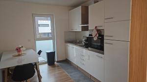 a kitchen with white cabinets and a table and a window at Bright apartment, private parking in Dudelange