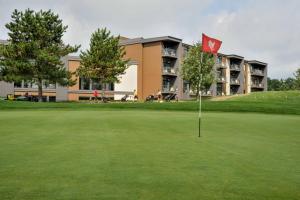 un campo de golf con bandera roja frente a un edificio en La Cache du Golf, en Beauceville