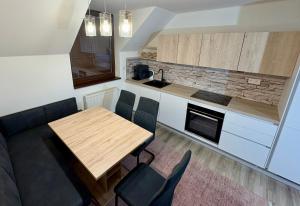 Una cocina y un comedor con mesa y sillas de madera. en Tatra Family Loft, en Vysoké Tatry
