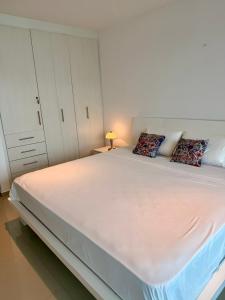 a bedroom with a large white bed with pillows at Departamento Diamond Beach Tonsupa in Tonsupa +9 photos