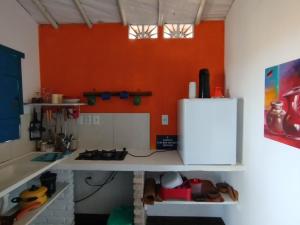 a kitchen with an orange wall and a white refrigerator at Cabanas Caraúbas II - ótimo visual do mar in Maxaranguape
