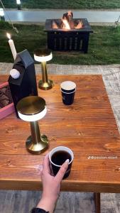 a person holding a cup of coffee on a wooden table at Passion 1 Al arid شاليه باشن حي العارض in Riyadh