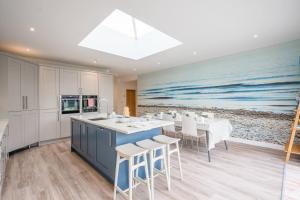 een keuken met een blauw eiland en een schilderij van de oceaan bij 100 Leiston Road, Aldeburgh in Aldeburgh