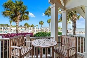 a porch with two chairs and a table and palm trees at SI2638: 2638 Seabrook Island Road in Seabrook Island