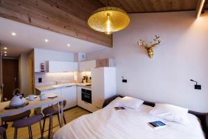 a bedroom with a bed and a table and a kitchen at RESIDENCE OLYMPIE 1 in Méribel