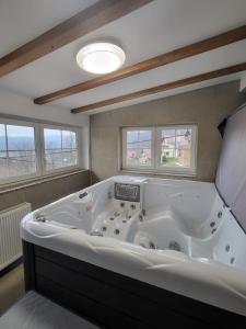 eine große weiße Badewanne in einem Zimmer mit Fenstern in der Unterkunft Kuća za 10 osoba s jacuzzijem i biljarom Mrkopalj in Mrkopalj