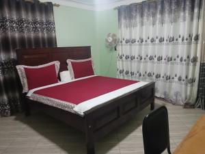 a bedroom with a bed with red and white pillows at Panda hotel in Entebbe
