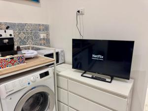 a laundry room with a tv and a washing machine at Anastasia's House in Palermo