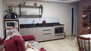 a living room with a kitchen and a couch at Casa aconchegante e familiar no bairro Vila Nova in Joinville +11 photos