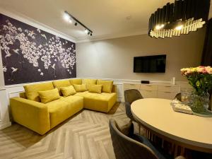 格但斯克Holiday Apartment Old Town Gdansk with a Jacuzzi的客厅里有一张黄色的沙发和一张桌子