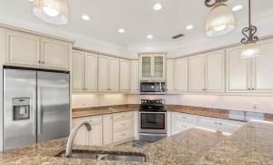 una cucina con mobili bianchi e un frigorifero in acciaio inossidabile di Lakeside Retreat with pool, dock & game room a Interlachen