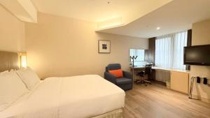 a hotel room with a bed and a chair and a desk at Holiday Inn Express Taoyuan by IHG in Taoyuan