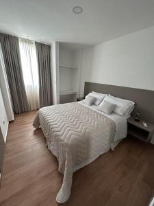 a bedroom with a large bed with white blankets and pillows at MorenoPLAZA in Concepción del Uruguay