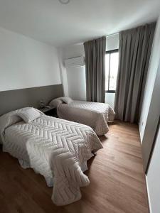 a bedroom with two beds and a window at MorenoPLAZA in Concepción del Uruguay +17 photos