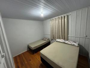 a small room with two beds and a window at Casa Átrio em Biguaçu próximo às Praias in Biguaçu