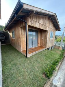 a wooden house with a large window on a yard at Casa Átrio em Biguaçu próximo às Praias in Biguaçu