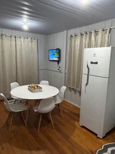 a room with a table and a white refrigerator at Casa Átrio em Biguaçu próximo às Praias in Biguaçu