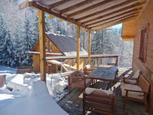 a porch of a cabin with a table and chairs in the snow at Chaty Jelenye in Turzovka