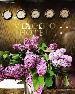 a bunch of clocks on a wall with purple flowers at V by Viaggio in Yerevan