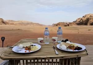 a wooden table with plates of food and bottles of water at MIRNA lUXURY CAMP in Wadi Rum