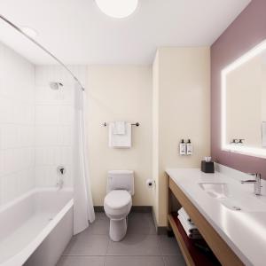 a bathroom with a toilet and a tub and a sink at Garner Hotel Pigeon Forge Downtown by IHG in Pigeon Forge