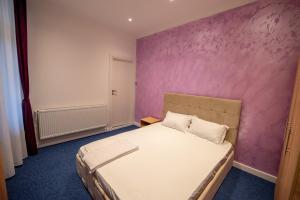 ein Schlafzimmer mit einem Bett mit einer lila Wand in der Unterkunft Vibe Studio Centrul Vechi Craiova in Craiova