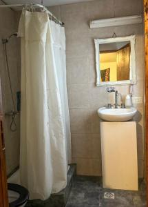 a bathroom with a white shower curtain and a sink at Hostel La Fortaleza in Bialet Massé +20 photos