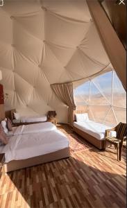 two beds in a tent with a view of the desert at MIRNA lUXURY CAMP in Wadi Rum