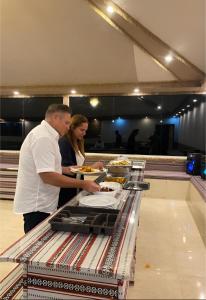a man and a woman standing in front of a buffet at MIRNA lUXURY CAMP in Wadi Rum