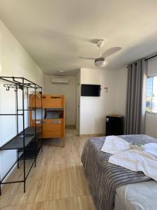 a bedroom with a bed and a desk and a ceiling fan at Pousada VKG Suites in São Pedro da Aldeia