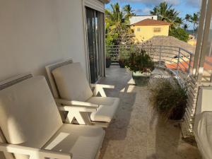 a balcony with two white chairs on a building at Condo cozy 1bdr 1bth in Punta Cana