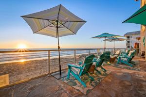 a group of chairs and umbrellas on the beach at Seashore On The Sand in Carlsbad